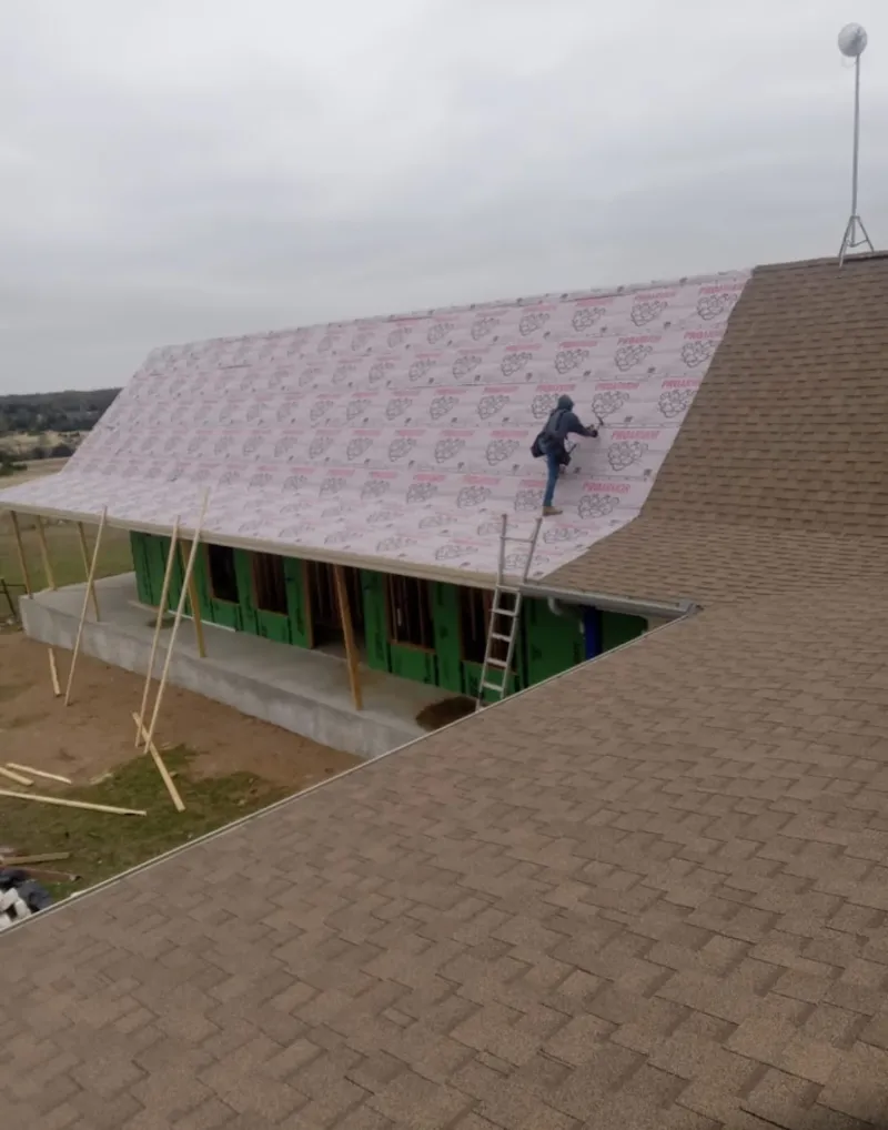 Worker preparing underlayment for a metal roof installation in Enterprise